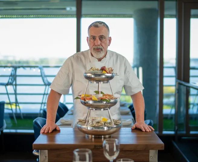 Chef Thomas Crenshaw stands beside an elegant seafood tower display