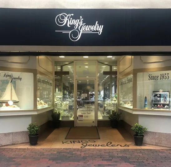 Storefront of King’s Jewelry with glass displays of jewelry, potted plants by the entrance, and signs reading Since 1955 and Kings Jewelry above and on the windows.