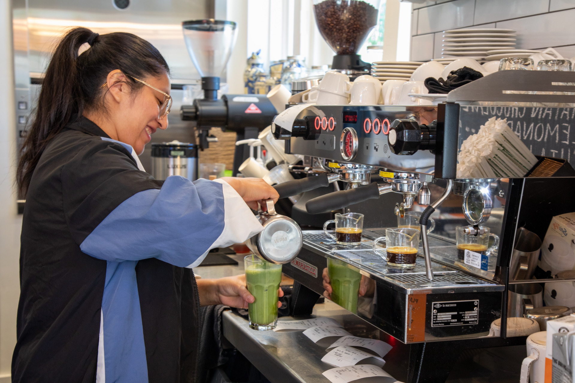 An image of a staff member at La
   Pluma Coffee & Wine Bar carefully creating a drink.