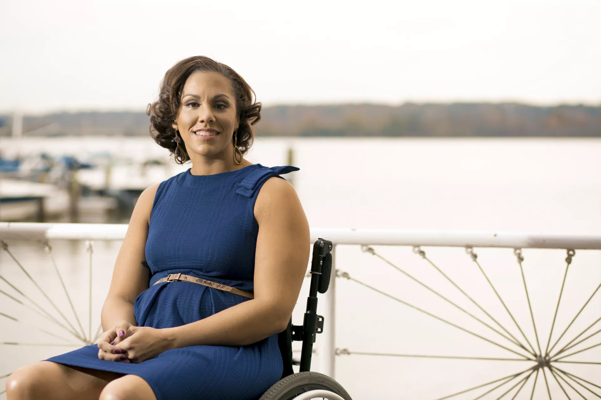 A young woman in a wheelchair sits in front of the Potomac River on a marina dock.