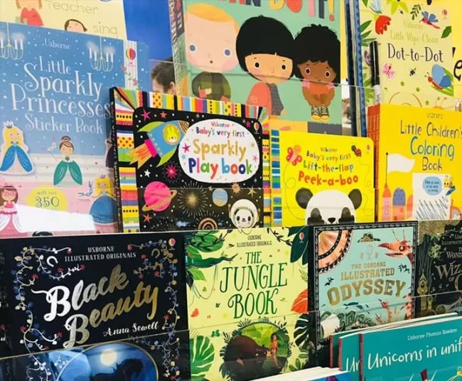 A colorful display of childrens books, including titles like Black Beauty, The Jungle Book, Sparkly Play Book, and Little Childrens Coloring Book, arranged upright and overlapping on a shelf.