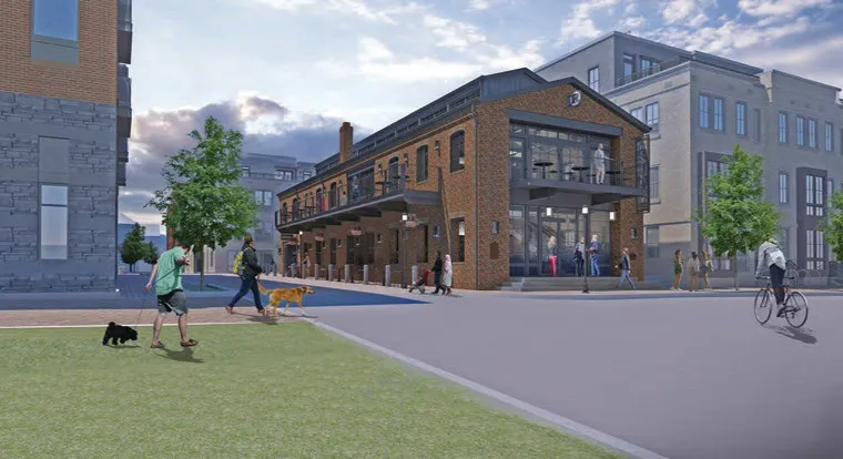 A modern urban street scene with people walking, biking, and walking dogs near a renovated brick building with large windows and a balcony, surrounded by newer buildings and greenery under a partly cloudy sky.