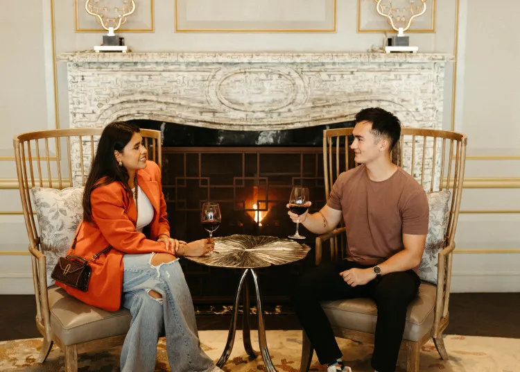 Couple standing by fireplace in elegant hotel lobby