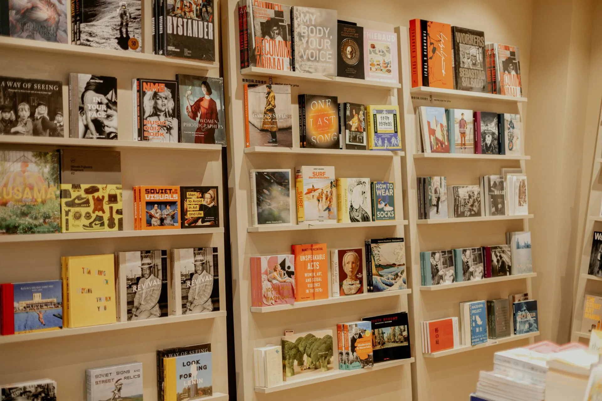 Bookshelves displaying a variety of colorful books and magazines, arranged neatly with covers facing outward. The shelves are filled with different genres, creating a vibrant and inviting bookstore atmosphere.