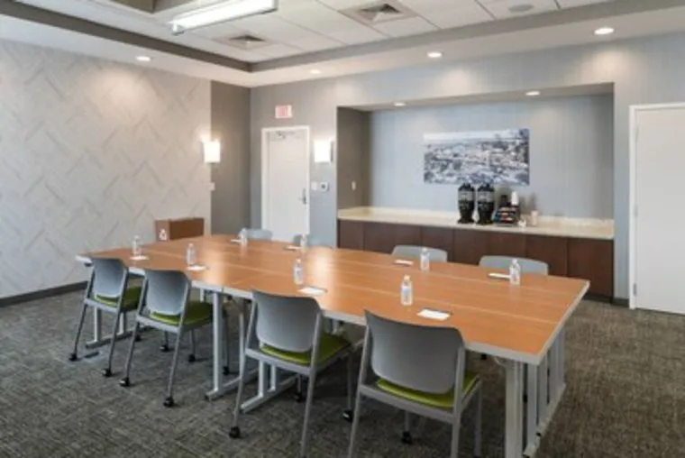 Naturally lit boardroom with a long conference table and gray chairs.