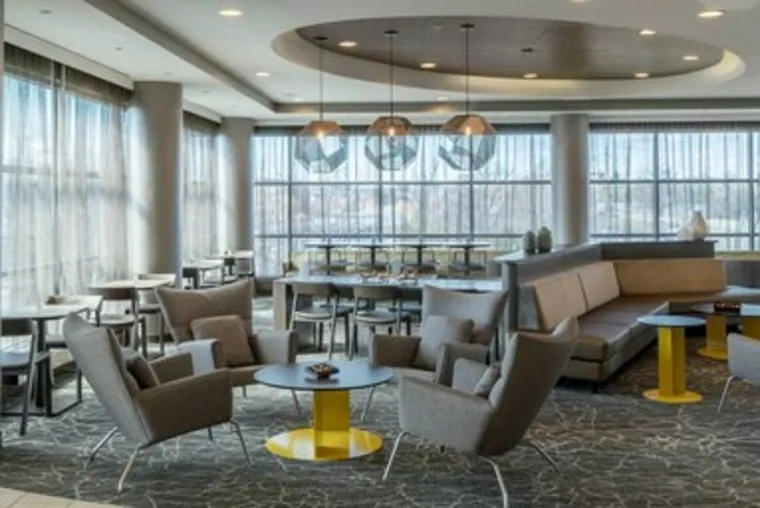 Modern hotel lobby seating area with armchairs, couches, and coffee tables.