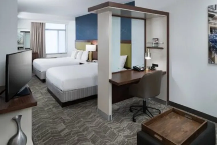 Hotel suite with two queen beds, a partition wall, and a built-in desk with an office chair.