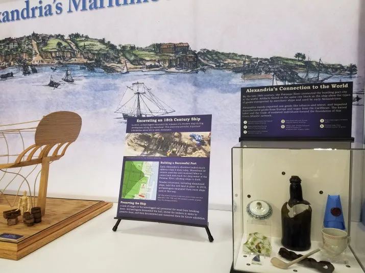 A museum display features historical artifacts, a ship model, and informational panels about Alexandrias maritime history, including a 19th-century ship excavation and Alexandria’s global connections.