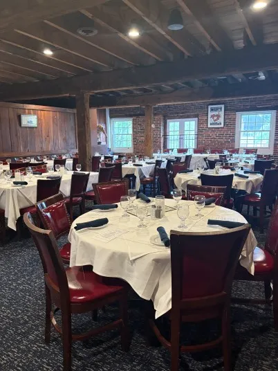 Private event space at The Wharf with round tables, white linens, and rustic wooden beams.