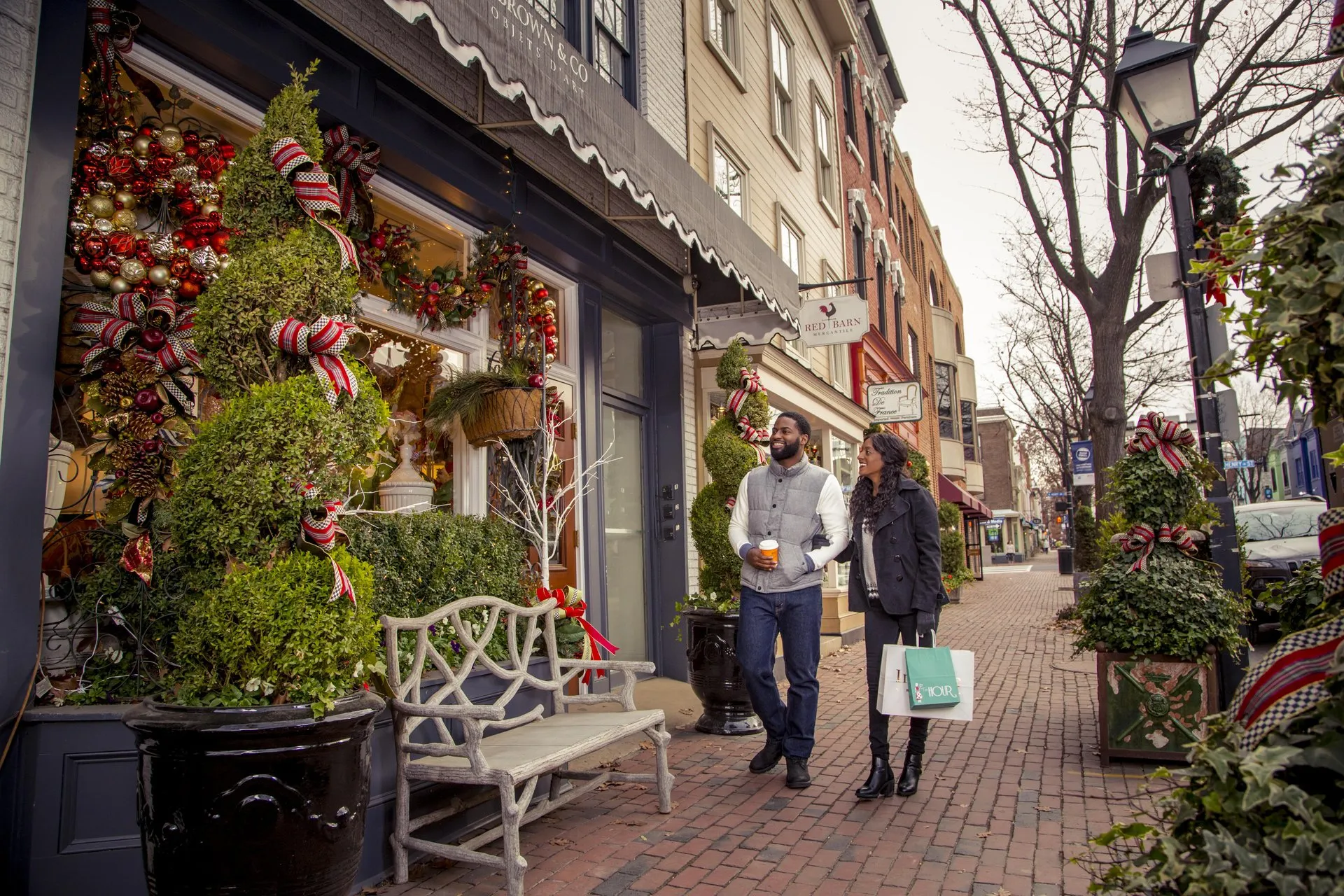 A man and woman stroll through down King Street in Alexandria, VA admiring holiday decorations.
