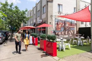 A man and woman smile and walk down Mount Vernon Avenue in Alexandria's Del Ray neighborhood.