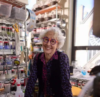 Artist Alison Sigethy smiling inside her Torpedo Factory Art Center glass studio.