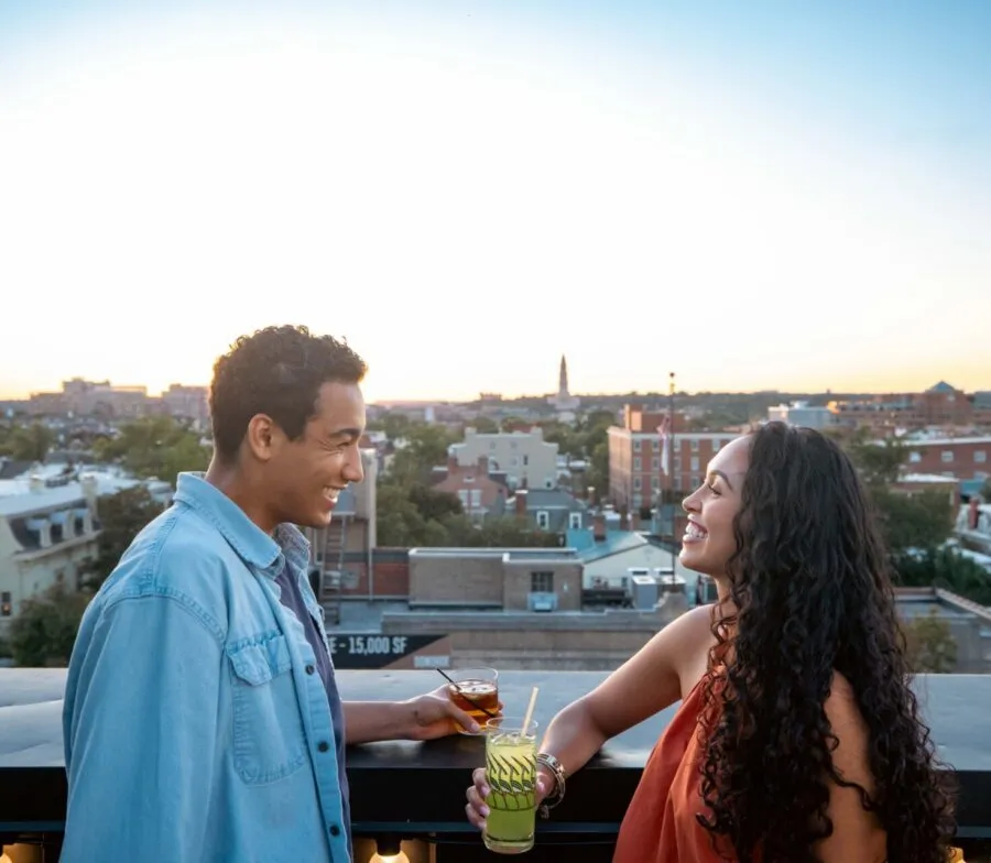 Couple enjoying cocktails at sunset on a rooftop overlooking Old Town Alexandria.