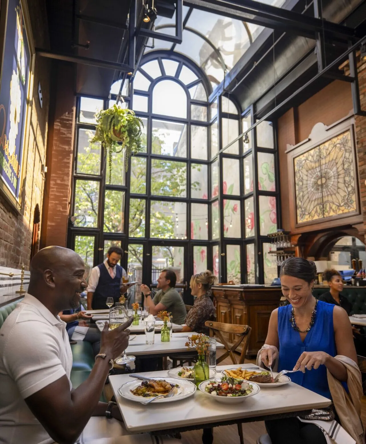 Guests dining inside a historic Old Town Alexandria restaurant with skylight and Parisian décor.