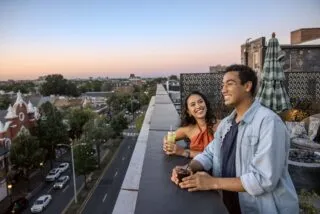 Couple enjoying drinks on an Alexandria rooftop at sunset overlooking King Street and Old Town.