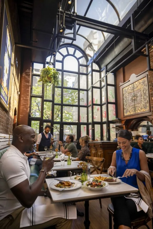 Guests enjoying French dining beneath a skylight in a historic Old Town Alexandria restaurant.