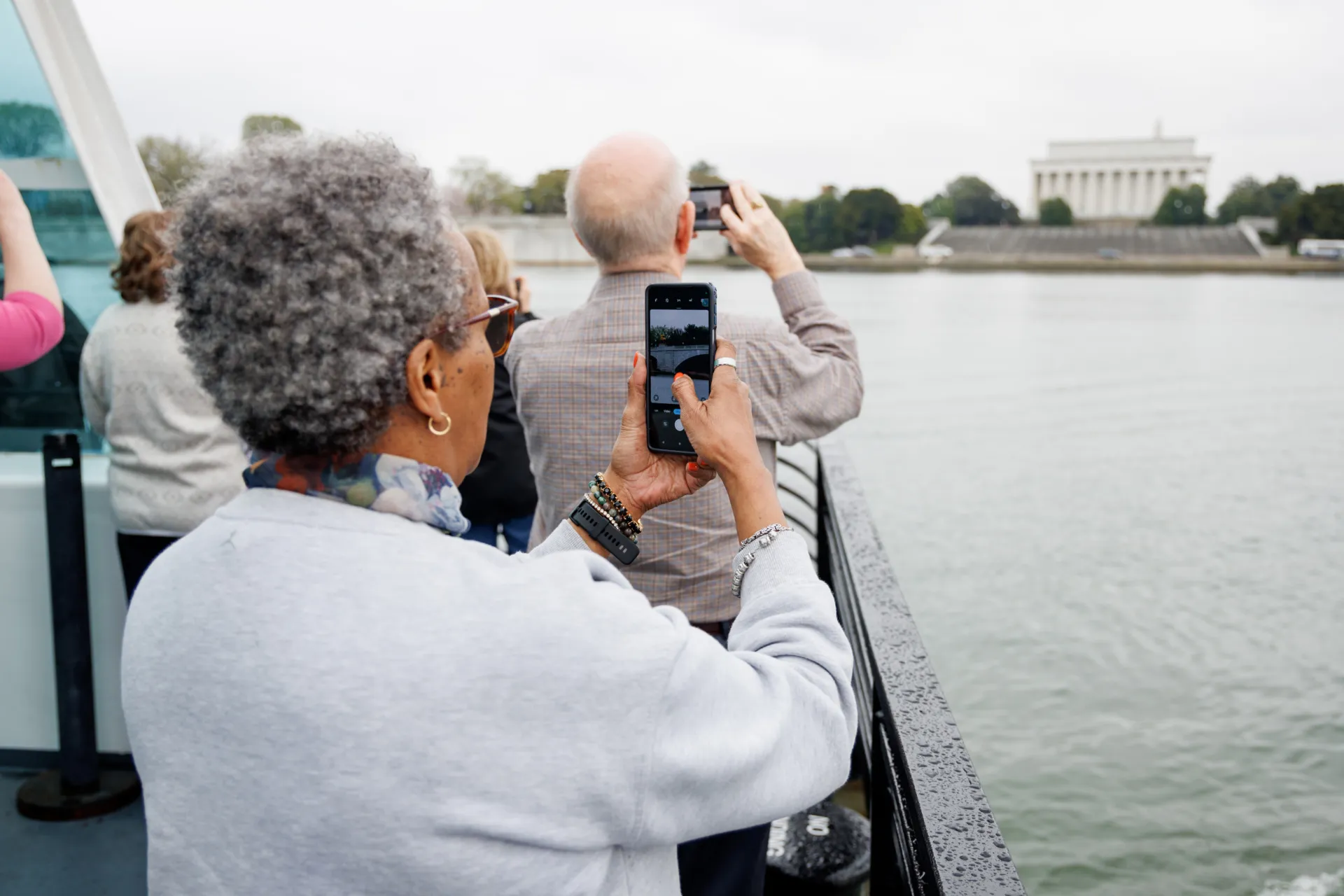 Passengers on a boat taking photos of the Jefferson Memorial during a Cherry Blossom Cruise.