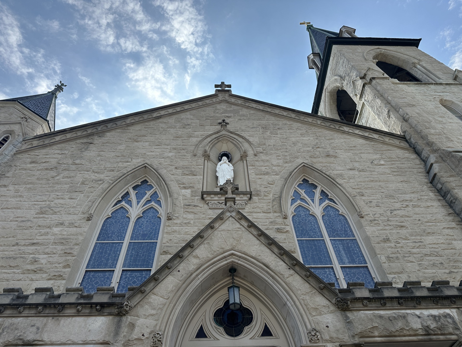 Exterior of the Basilica of Saint Mary in Alexandria showing stone arches and a statue of Mary.