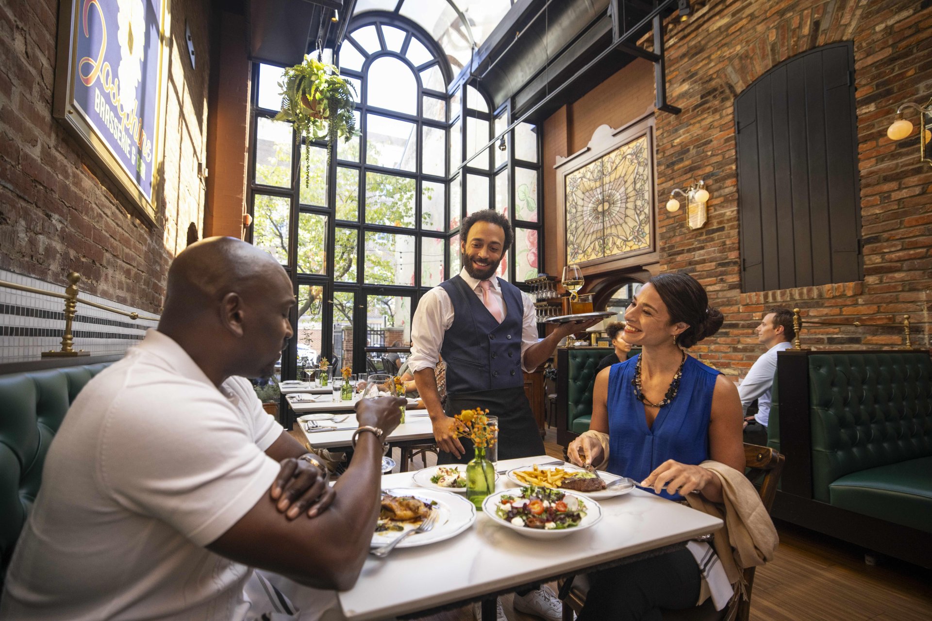 A man and woman smile while being served a meal at Josephine restaurant in Old Town Alexandria.