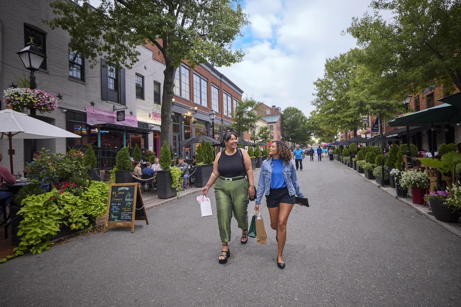 Two women holding shopping bags walk down historic King Street in Alexandria, VA.