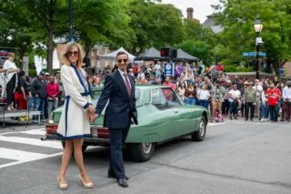 A stylish couple poses in front of a vintage green sports car on Alexandria's Historic King Street.