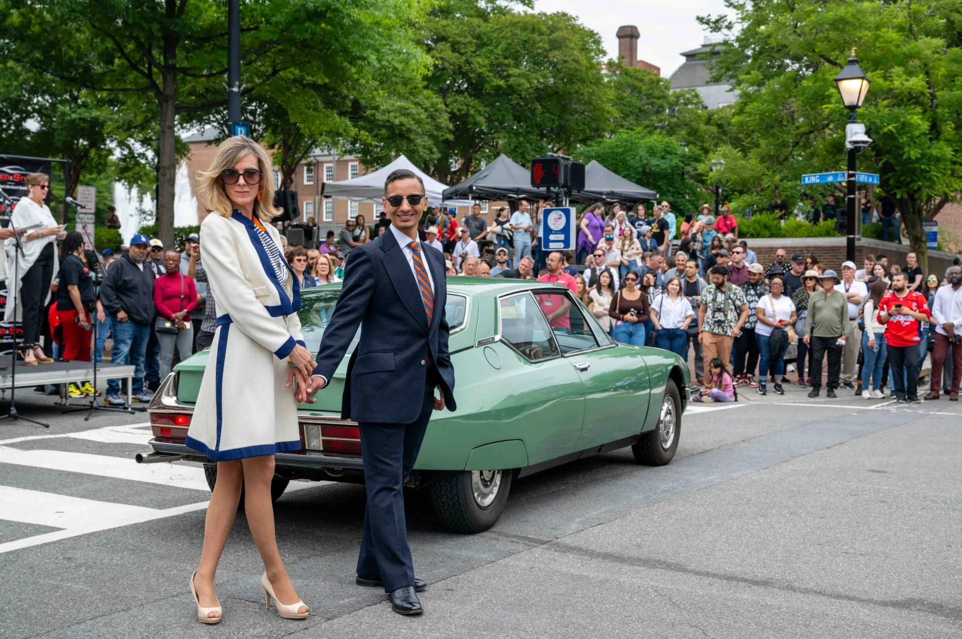 A stylish couple poses in front of a vintage green sports car on Alexandria's Historic King Street.