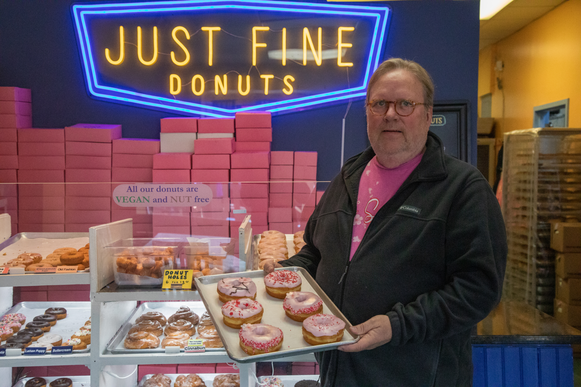 Just Fine Donuts owner Russell Gravatt holds a tray of freshly-baked cherry blossom donuts in front of his donut counter at his shop in Del Ray, Alexandria.