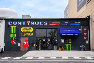 The exterior wall and front entrance of Continues Arcade features colorful video game themed font and graphics to welcome visitors inside.