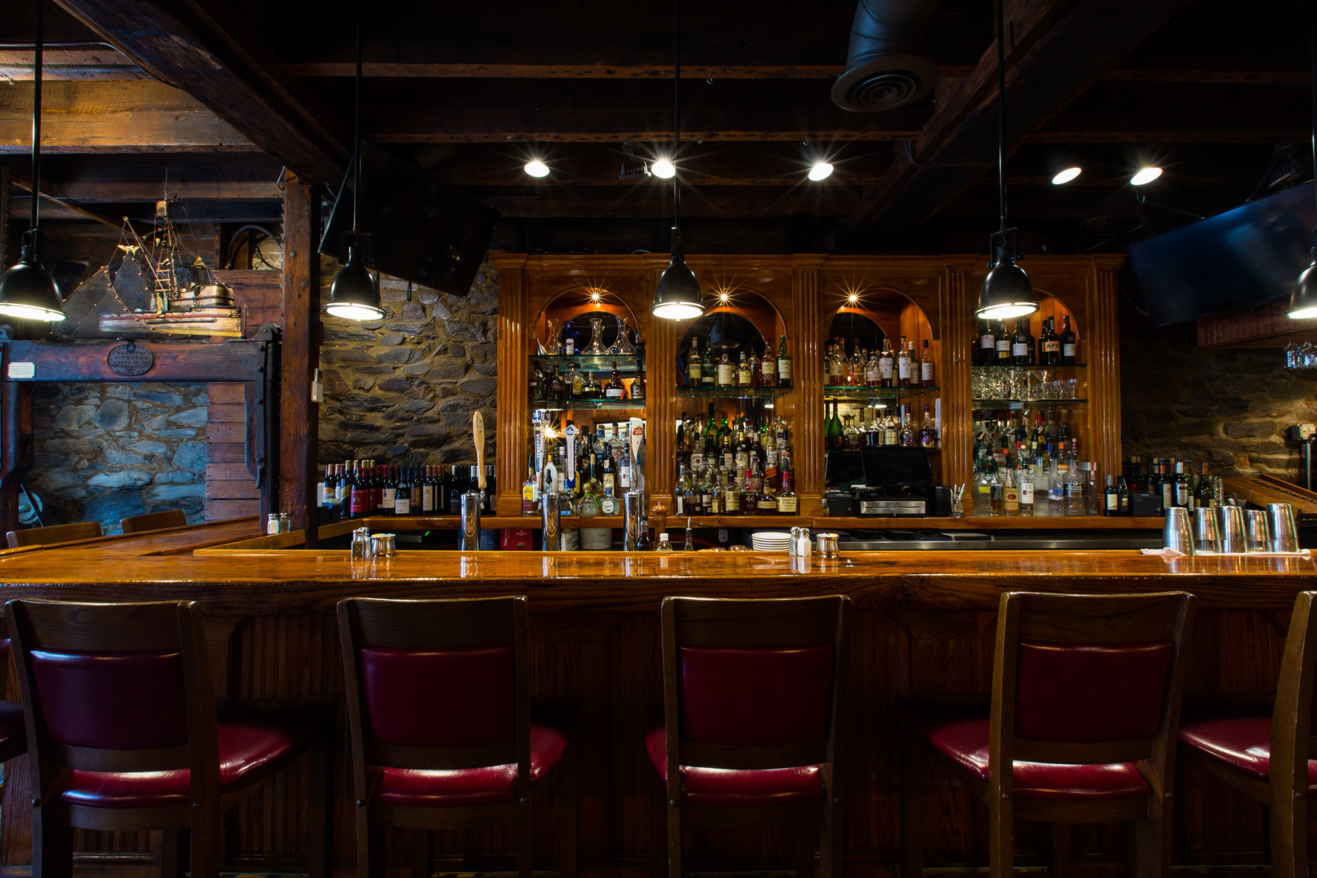 A shiny, wood-paneled bar at The Wharf features a full bar of spirits and liquor.