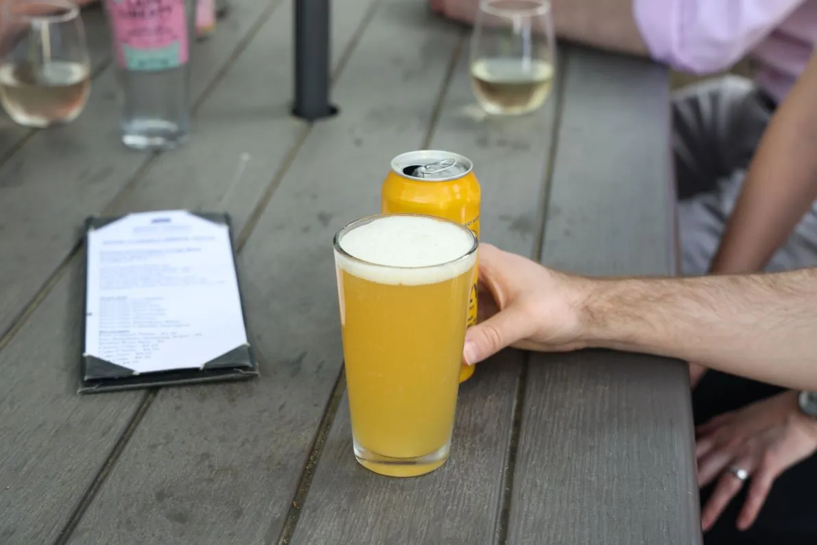 A hand reaching for a glass of beer on a table at the Beer Garden at Mount Vernon Inn Restaurant.