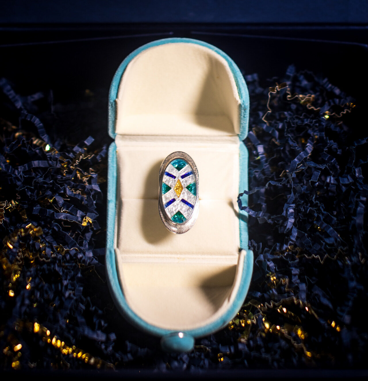 A close up view of Ana's jewelry showing mulit-colored gems inside a round shapes ring. 