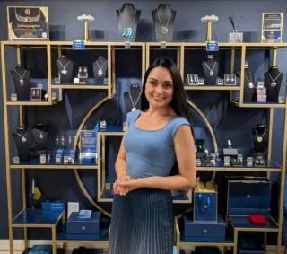 Ana Tkabladze posing in front of her jewelry display inside her art studio at the Torpedo Factory Art Center in Alexandria.