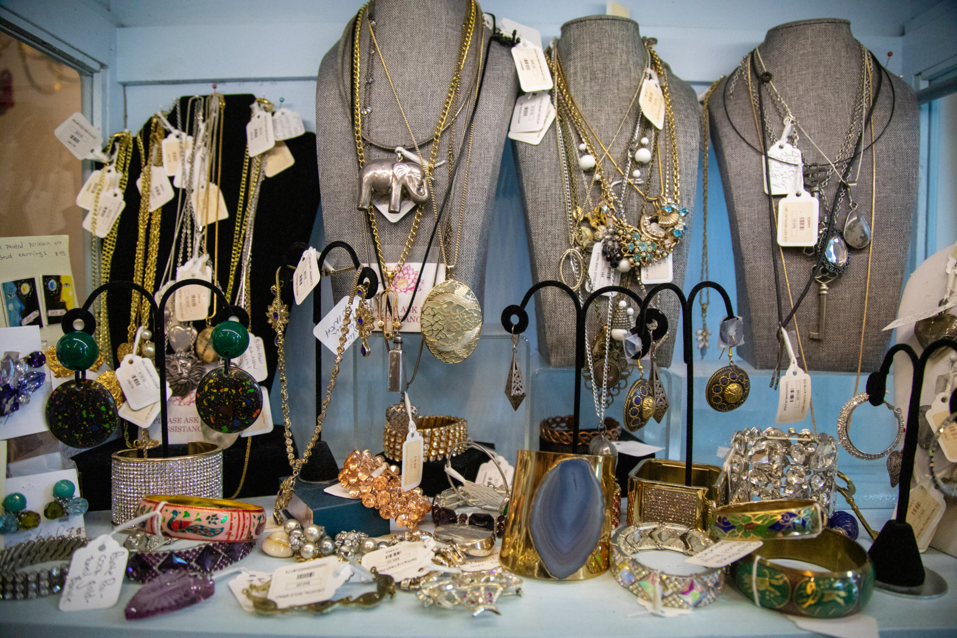 A collection of rustic vintage jewelry, necklaces, earrings, and bracelets stacked on top of each other in a crowded display.