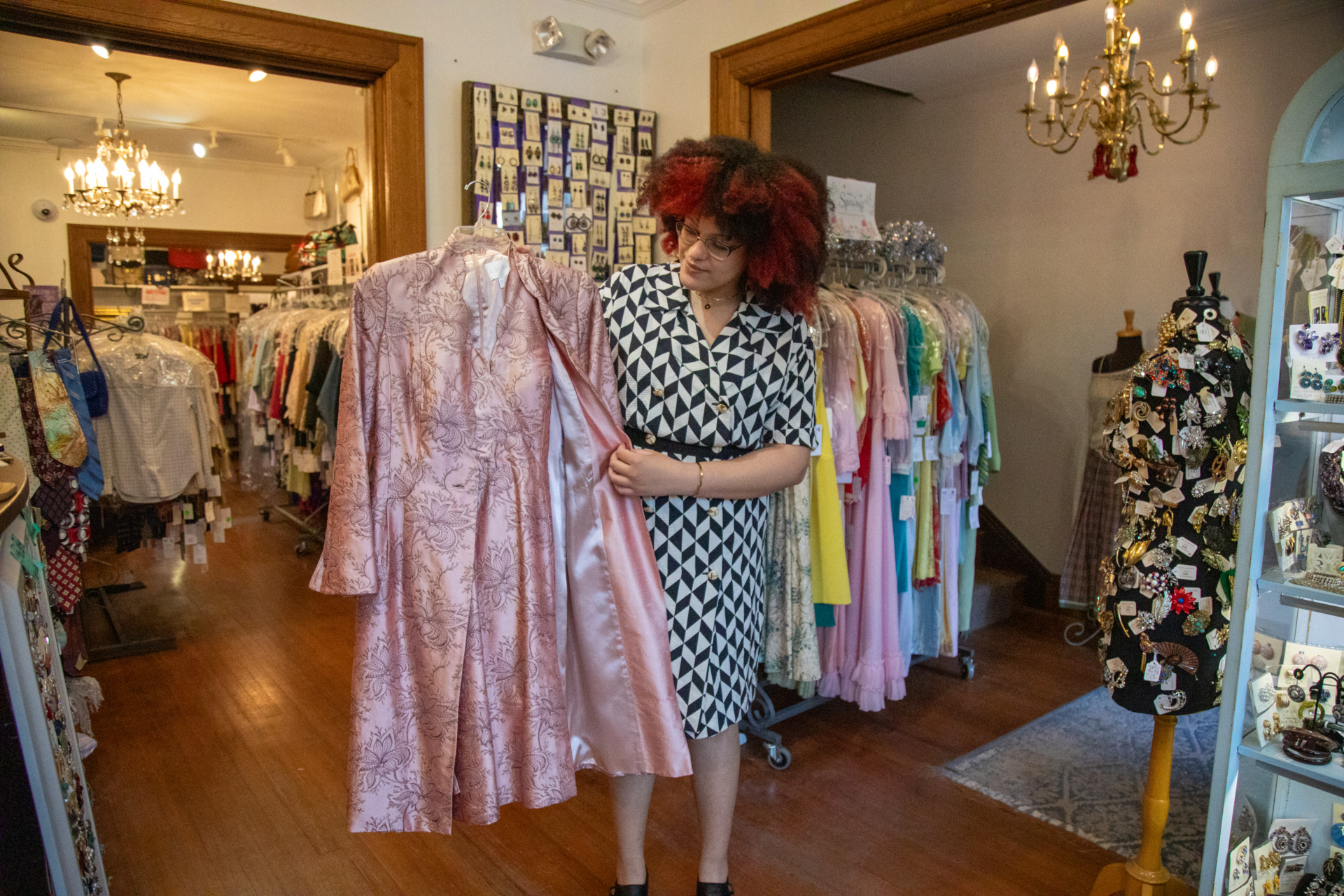 General manager Rebecca Jacobs holds up a vintage silk pink dress with ornate details. 