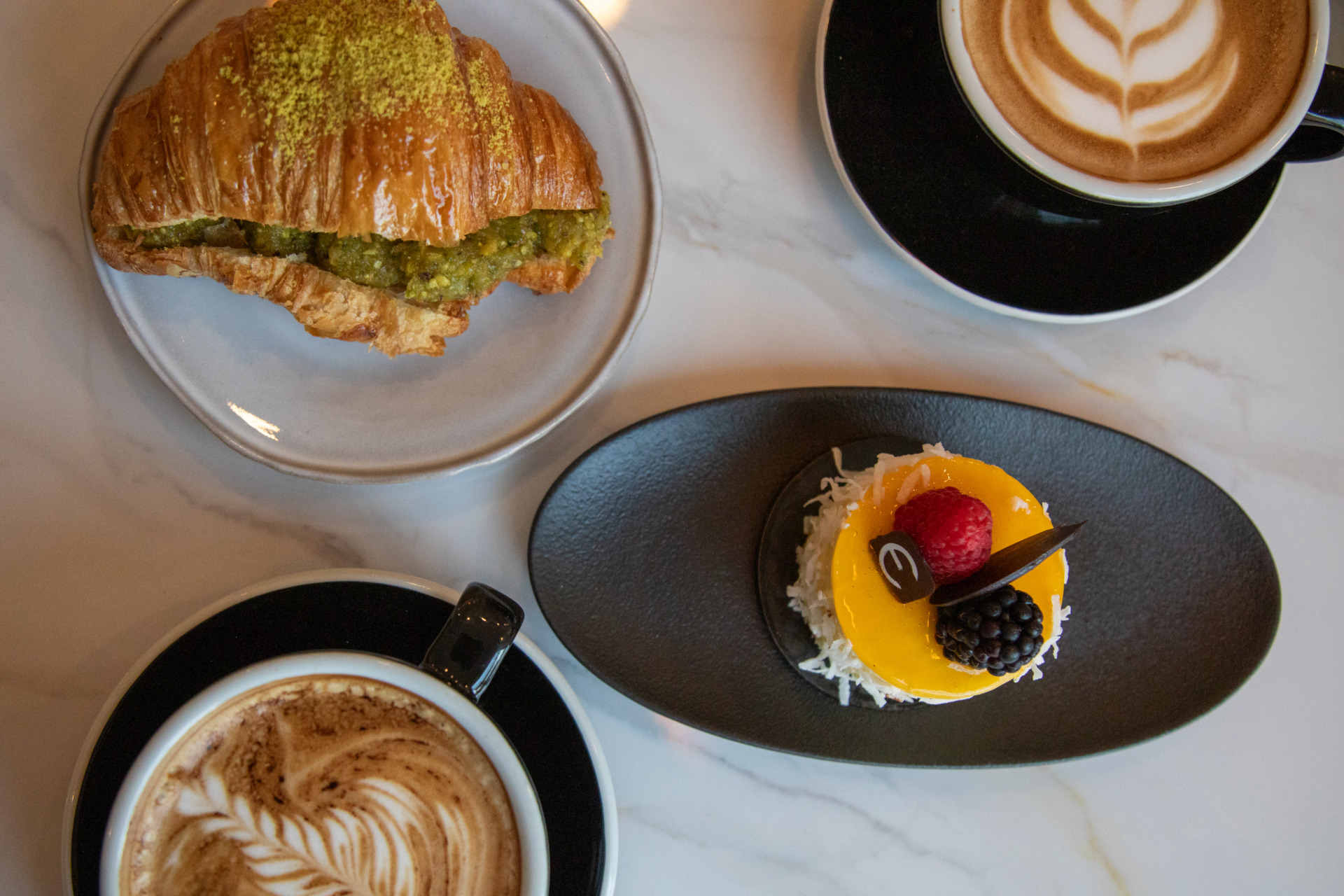 An aerial view of an assortment of pastries including croissants, coffee, and more.