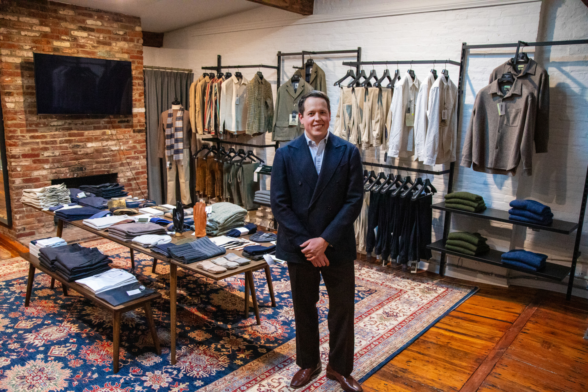 Drew Altizer standing inside Old House Provisions, surrounded by an assortment of menswear clothing items.