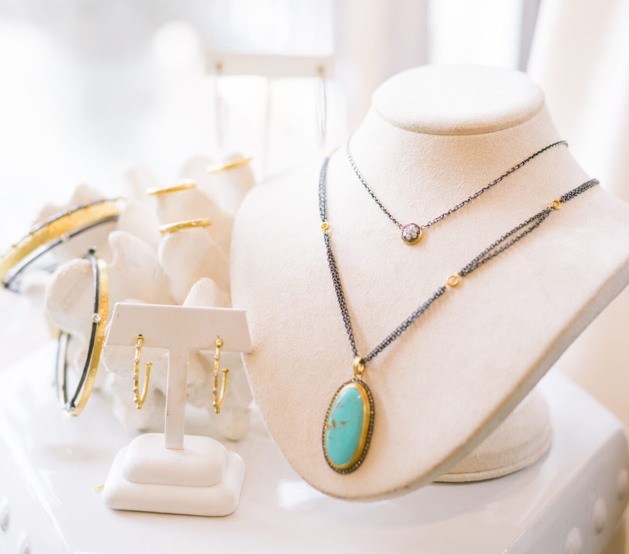 A collection of jewelry including necklaces, earrings, and a bracelet on a elegant stand. 