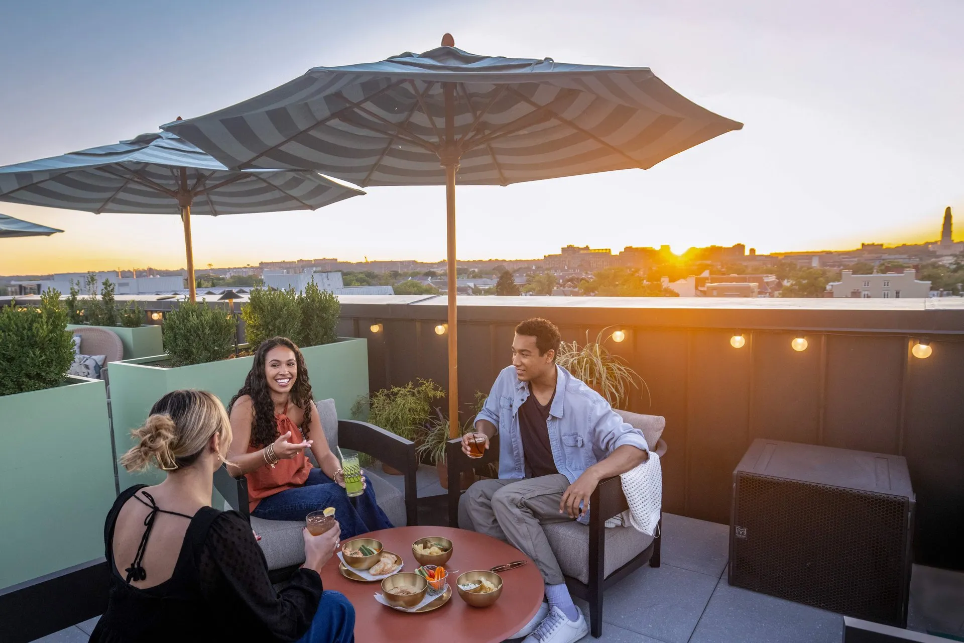 Friends enjoying food and drinks at Good Fortune rooftop restaurant at Hotel Heron in Old Town Alexandria.