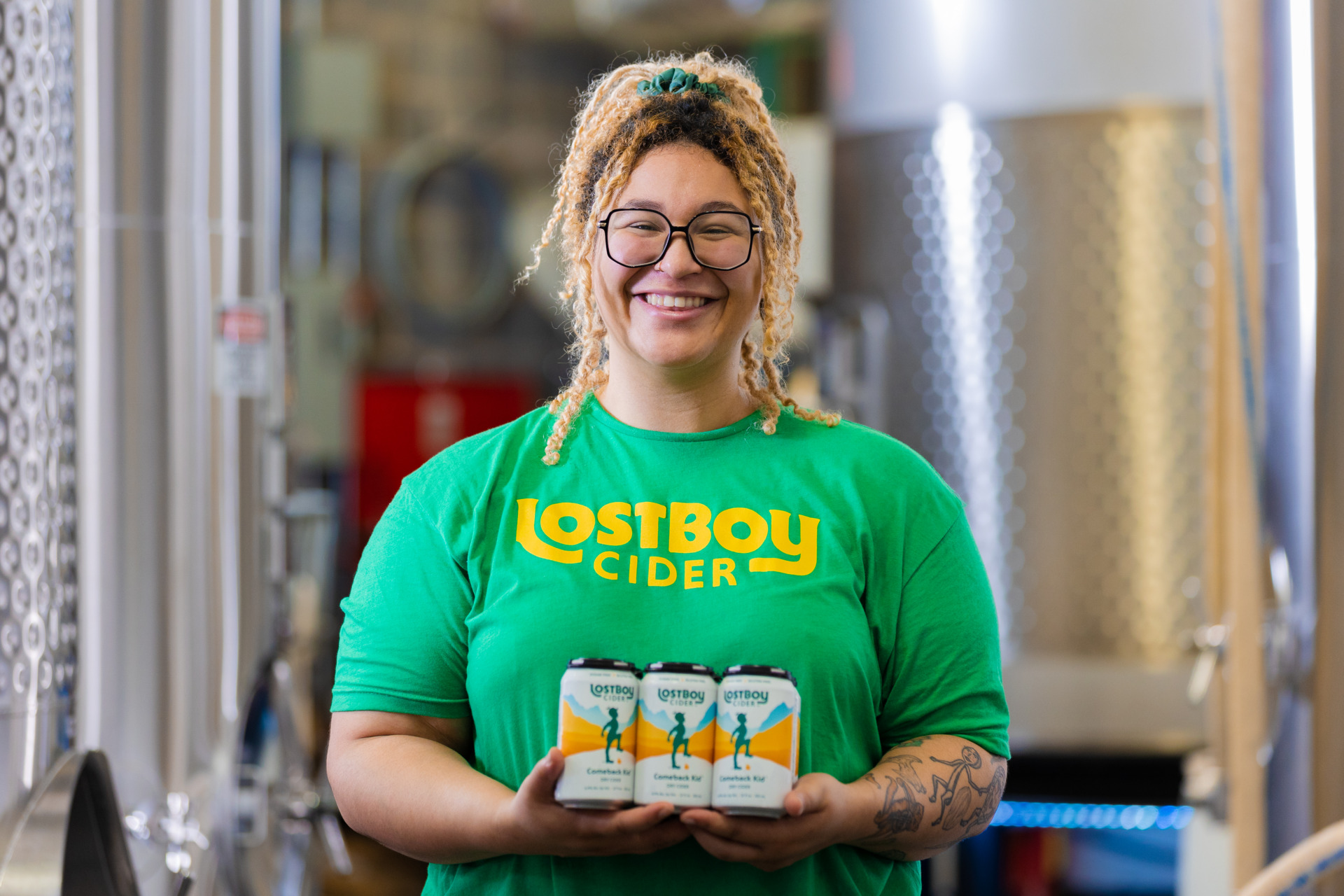 An image of a worker at Lost Boy Cider holding several cans of cider.