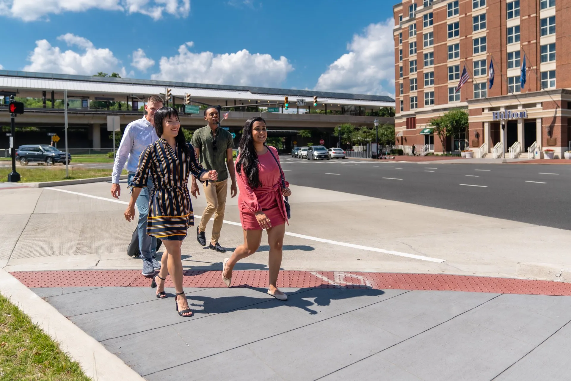 People in business attire stroll along King Street in Old Town Alexandria with a hotel in the background.