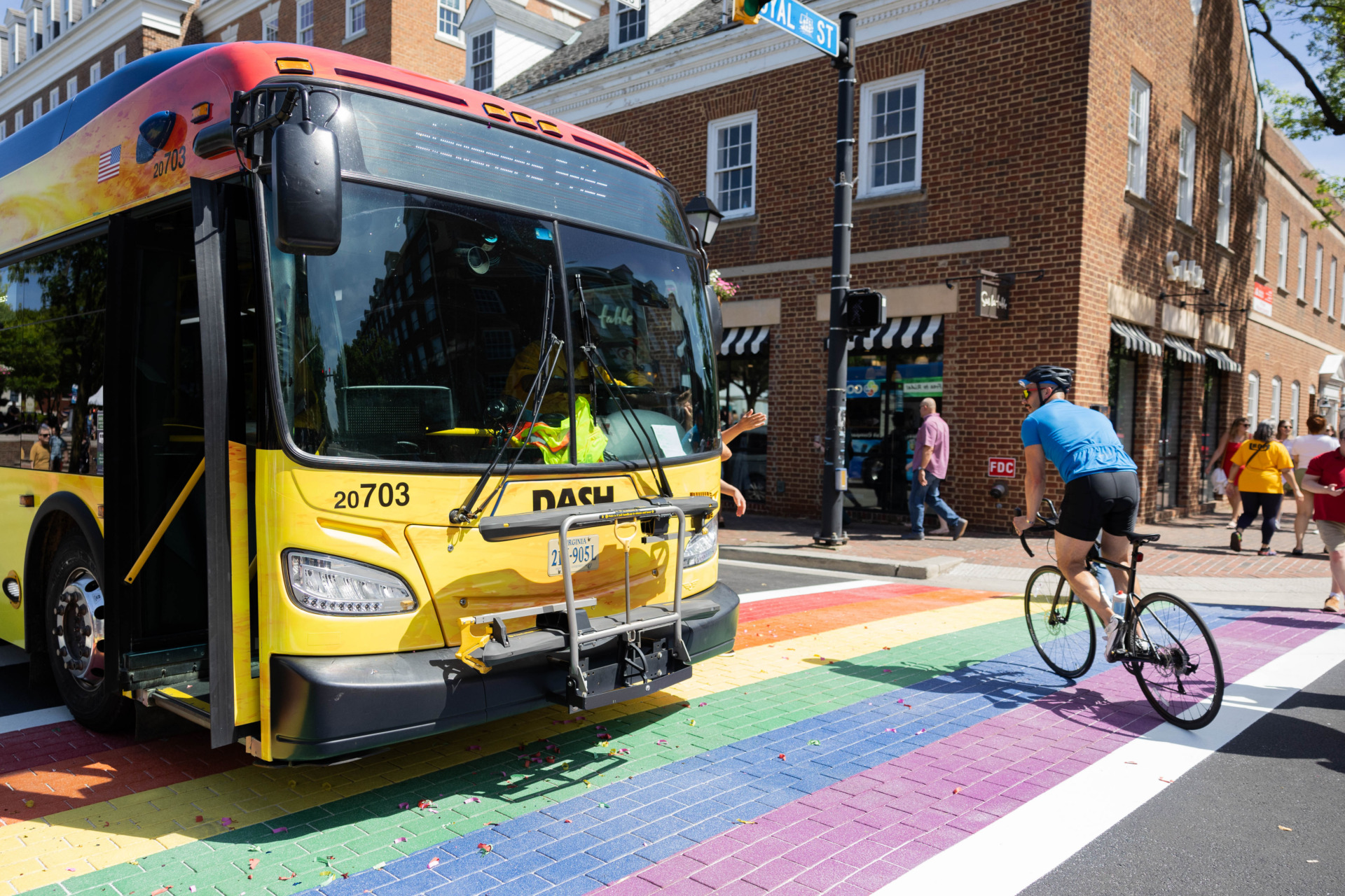 Alexandria's DASH bus wrapped in a pride design while driving along Alexandria's pride crosswalk. 