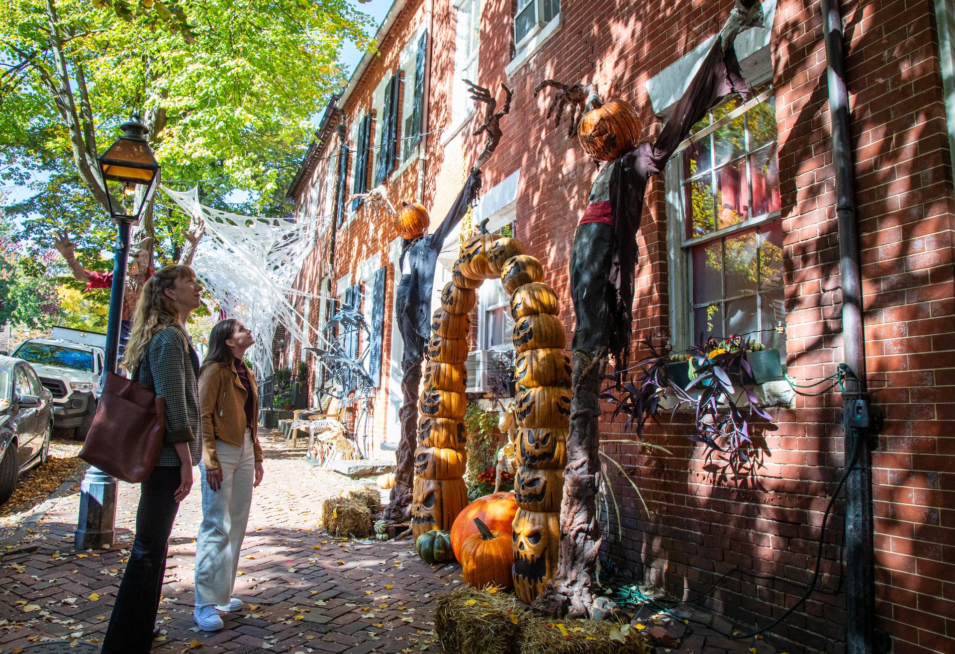 Two pedestrians looking at Halloween decorations on historic homes in Alexandria.
