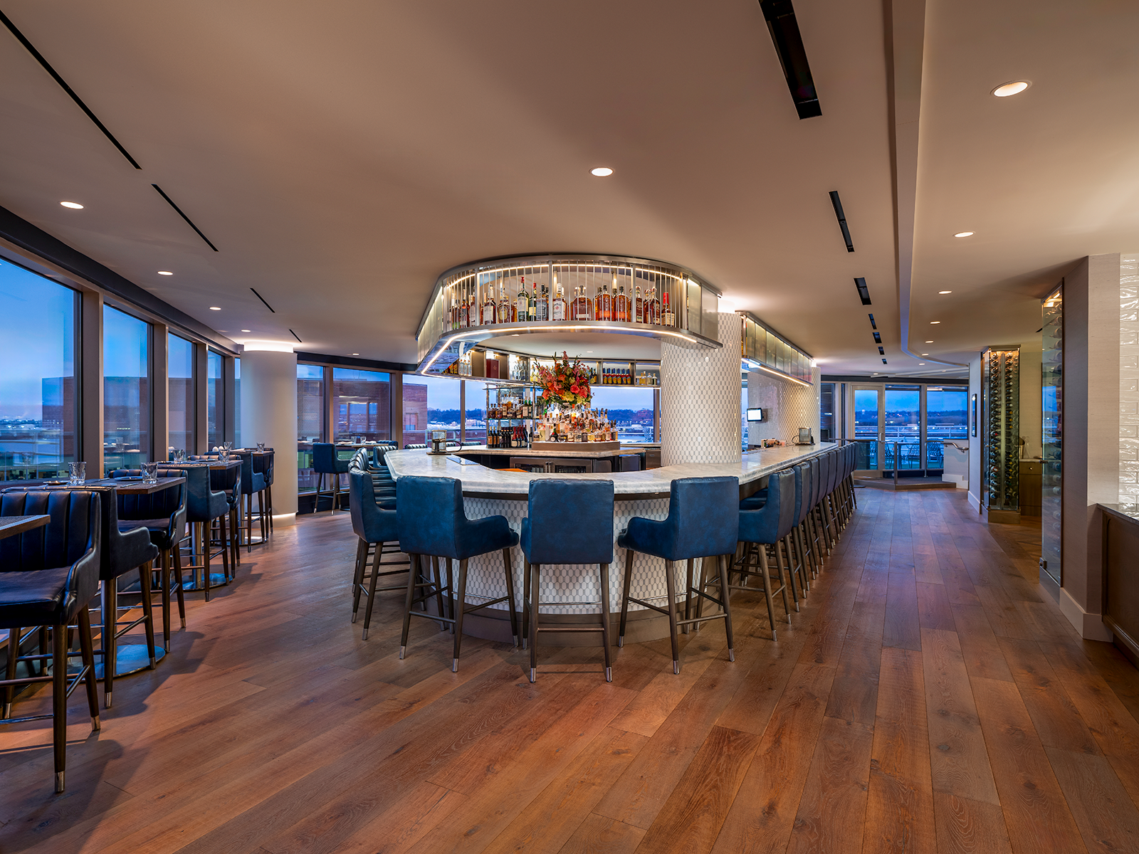 The bar and lounge at Jula's on the Potomac. Blue leather chairs make up the seating in the room while a stone white counter makes up the stylish bar. Drinks are carefully stored above the bar. 