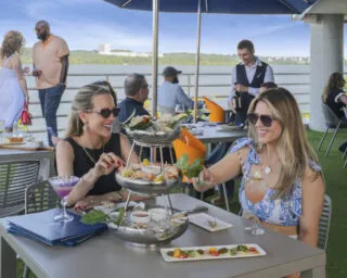 Two customers seated at a table and dining on the outdoor patio at Jula's on the Potomac. A view of the Potomac River is behind them.