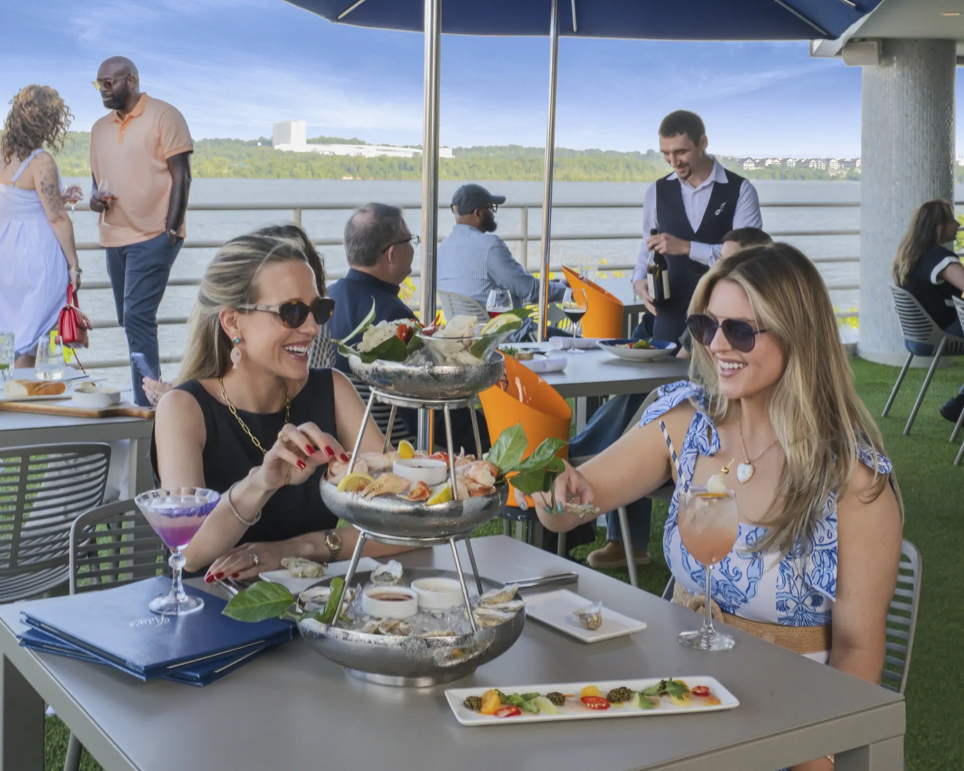 Two customers seated at a table and dining on the outdoor patio at Jula's on the Potomac. A view of the Potomac River is behind them.