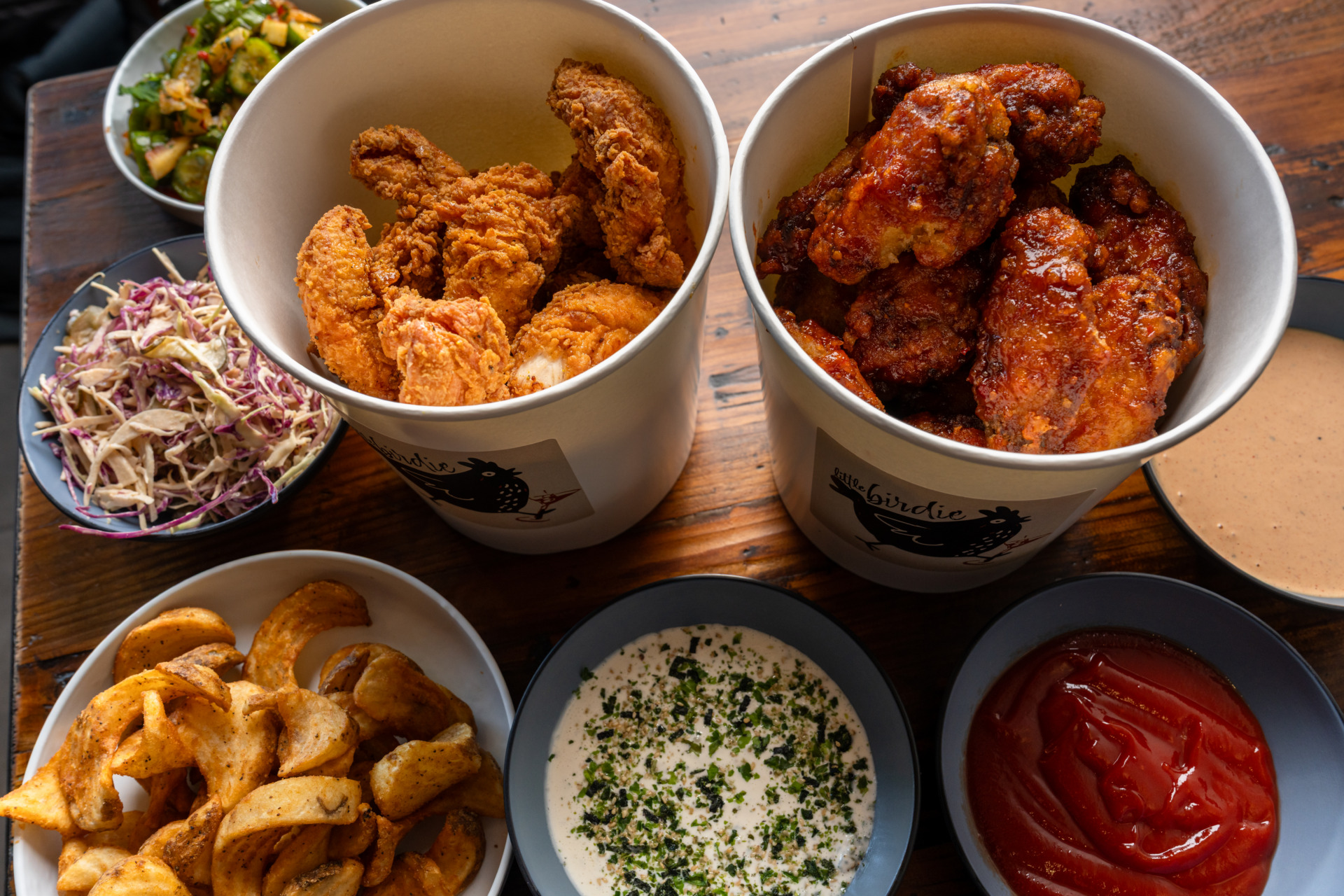 Little Birdie's bucket hour fried chicken pieces in round containers. 